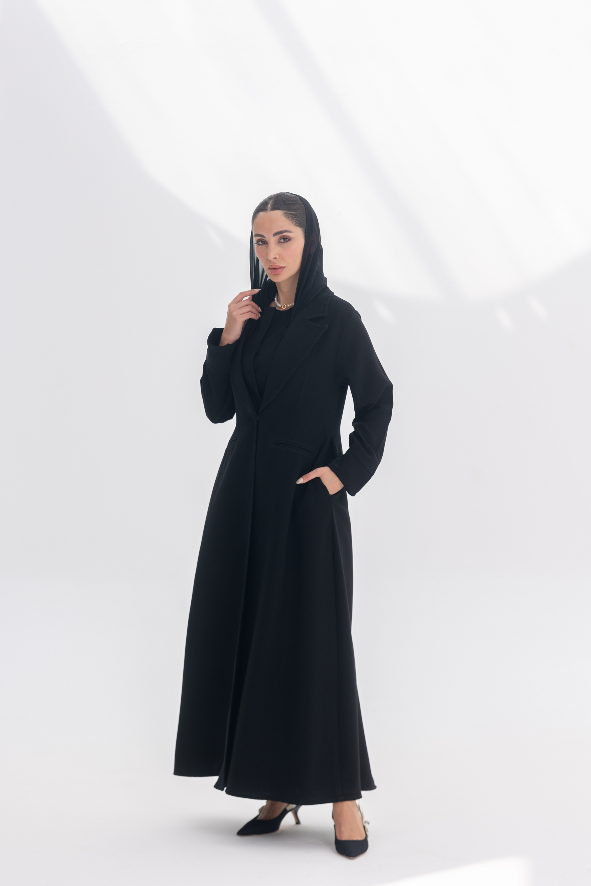 Woman wearing elegant black crepe blazer abaya with tailored silhouette and intricate embroidery, styled with matching black inner and pants.