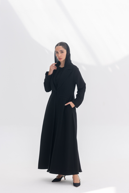 Woman wearing elegant black crepe blazer abaya with tailored silhouette and intricate embroidery, styled with matching black inner and pants.