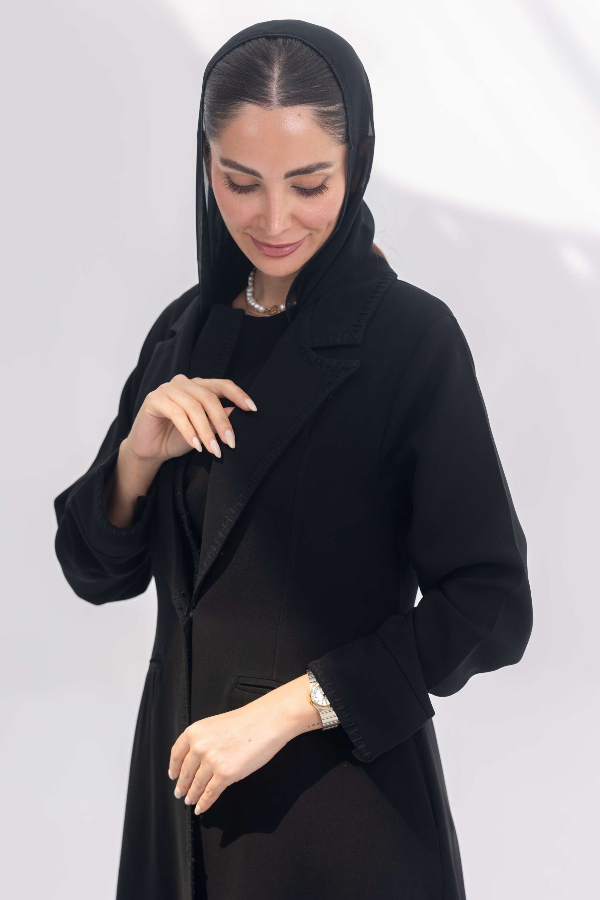 Woman wearing sophisticated black crepe blazer abaya with tailored silhouette and intricate black embroidery.