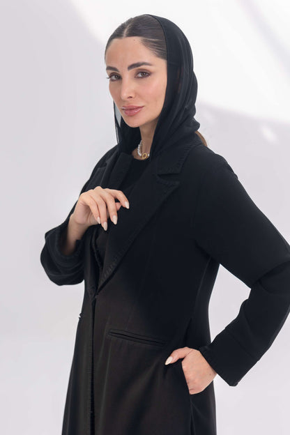 woman wearing a tailored black crepe blazer with a hooded inner, posing against a white background