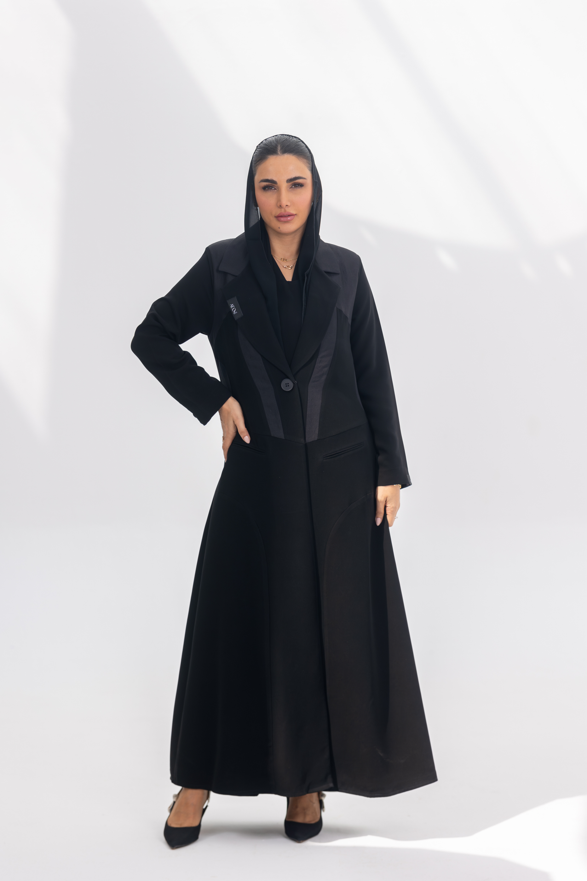 Woman wearing elegant black crepe Jetline abaya with dark grey accents and silk lining, front-open style.