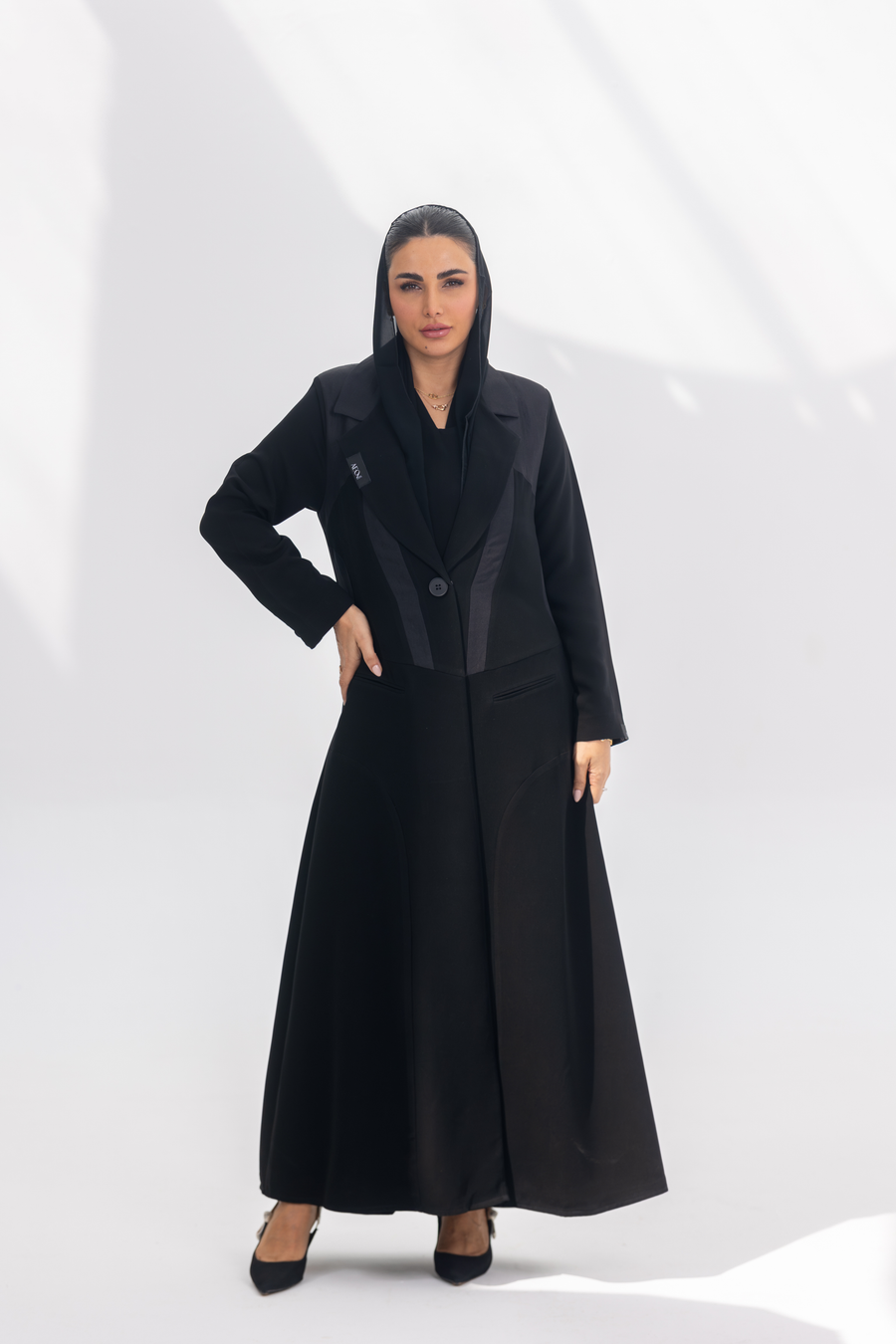 Woman wearing elegant black crepe Jetline abaya with dark grey accents and silk lining, front-open style.