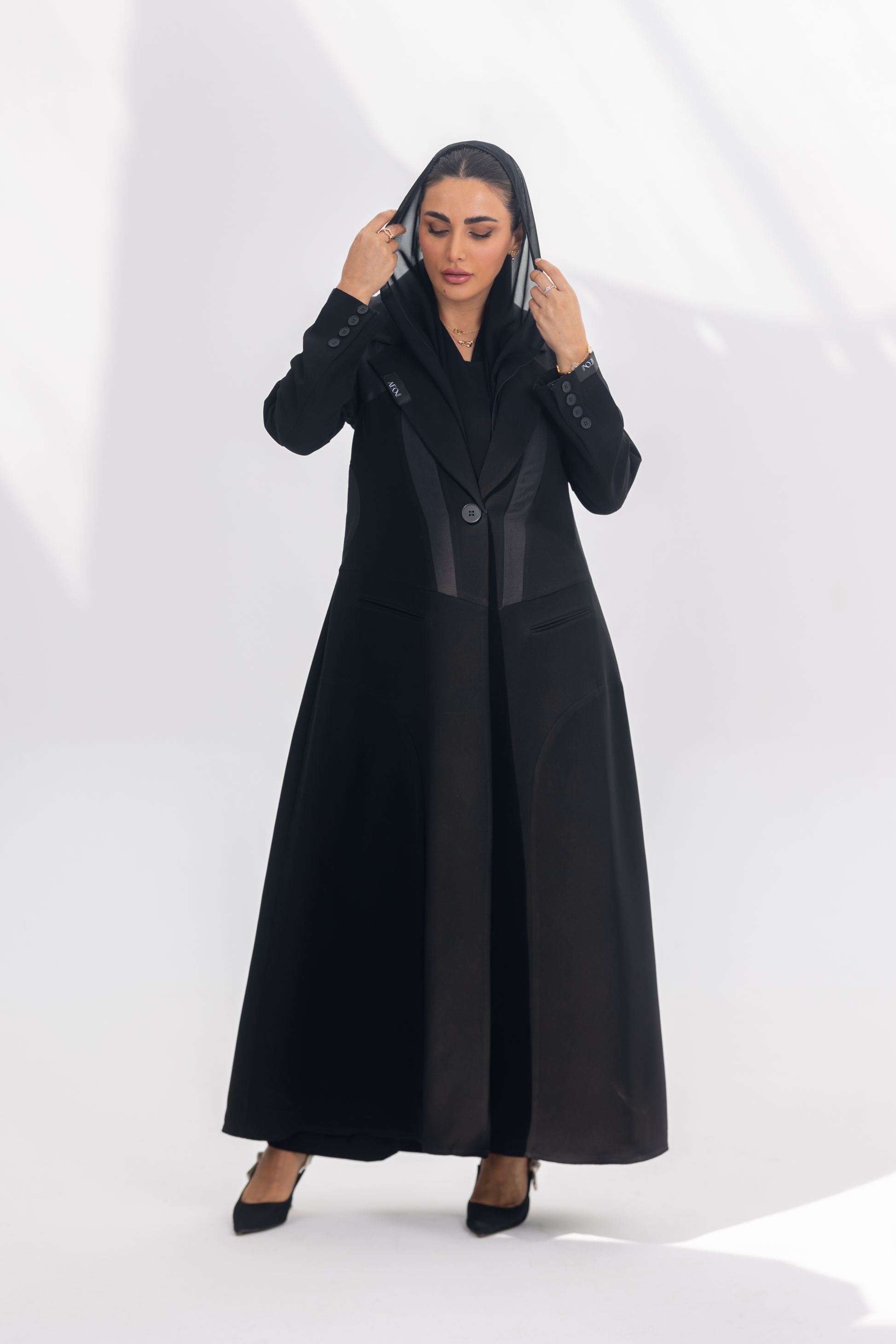Woman wearing elegant black crepe Jetline abaya with dark grey accents and silk lining.