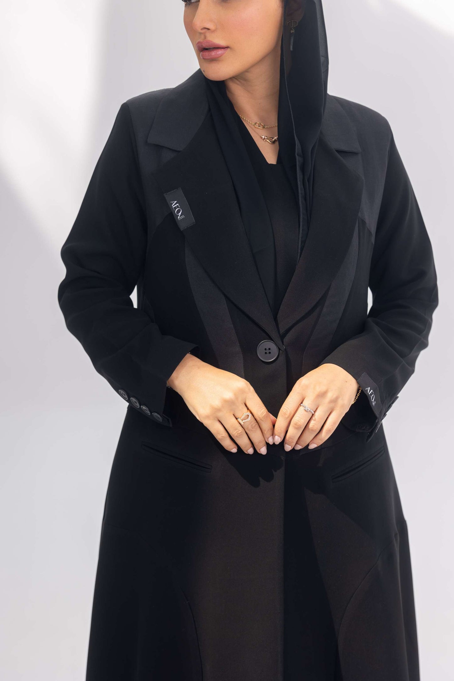 Elegant black crepe abaya with dark grey accents and silk lining, featuring a front-open design and sleek silhouette.