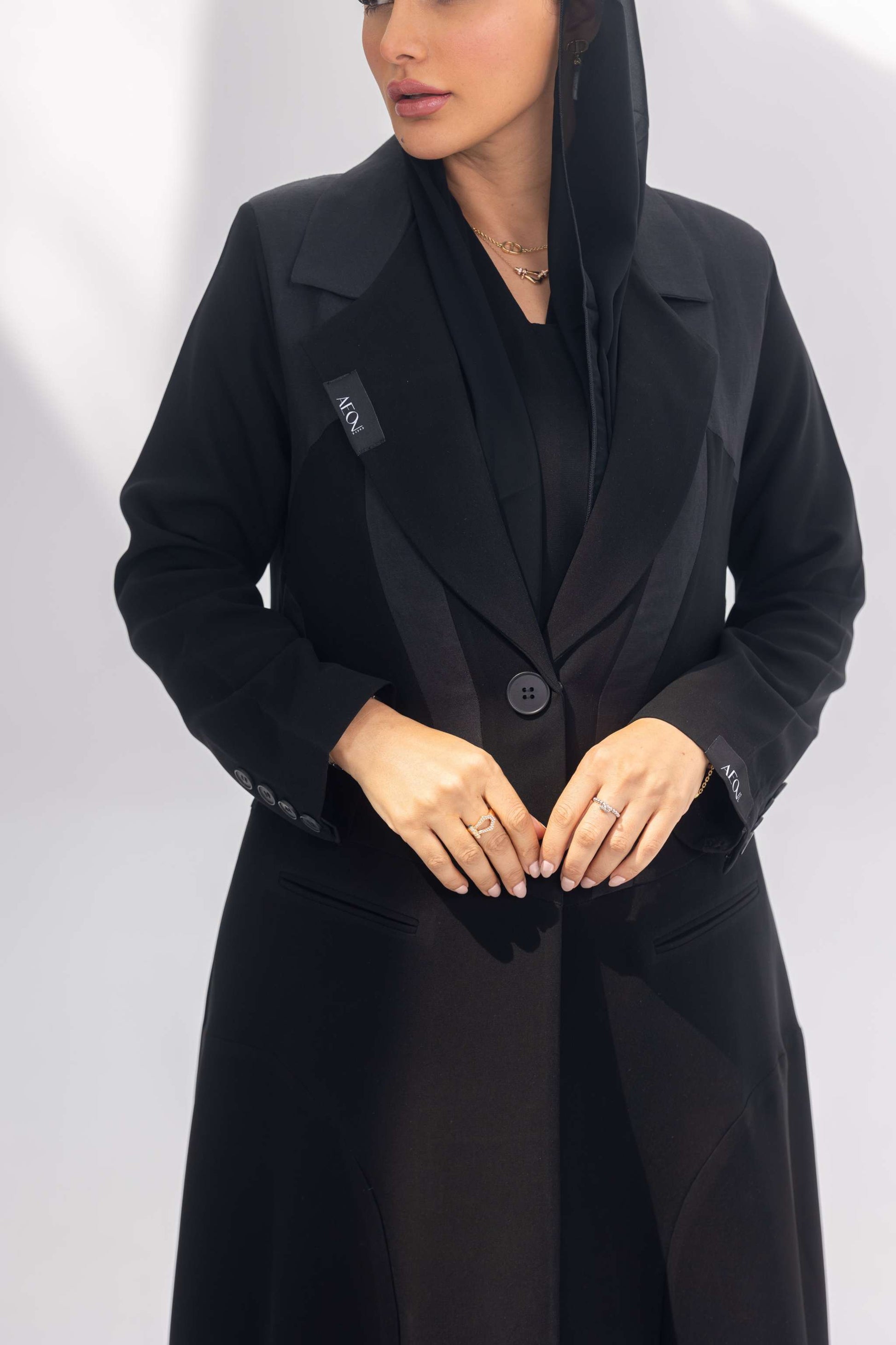 Elegant black crepe abaya with dark grey accents and silk lining, featuring a front-open design and sleek silhouette.