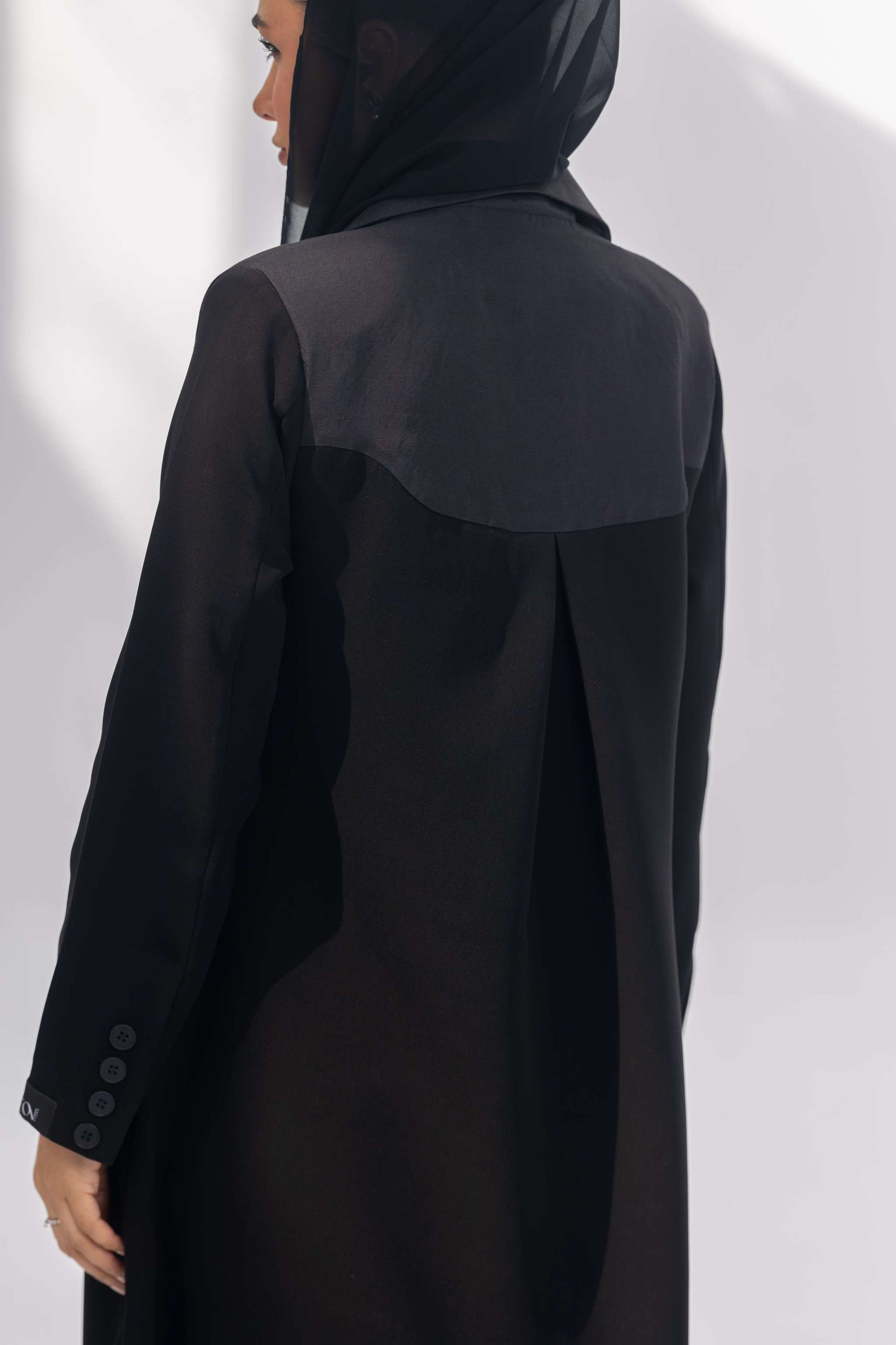 Black crepe abaya with dark grey fabric accents and sleek silhouette worn with a black hijab