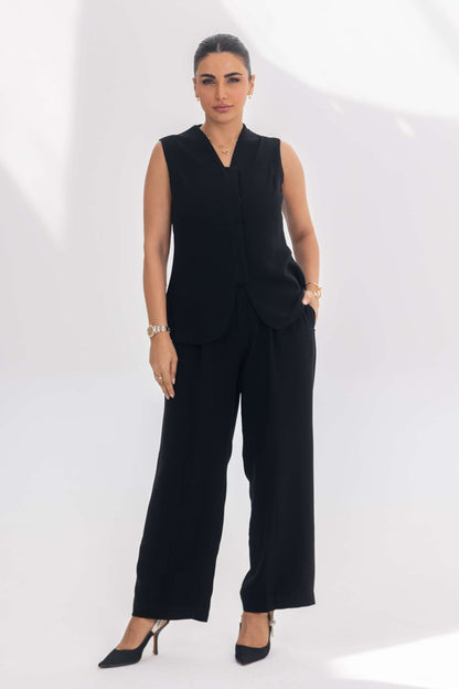 Woman wearing Noir Essential black crepe sleeveless top and wide-leg pants set with minimalist design and elegant silhouette.