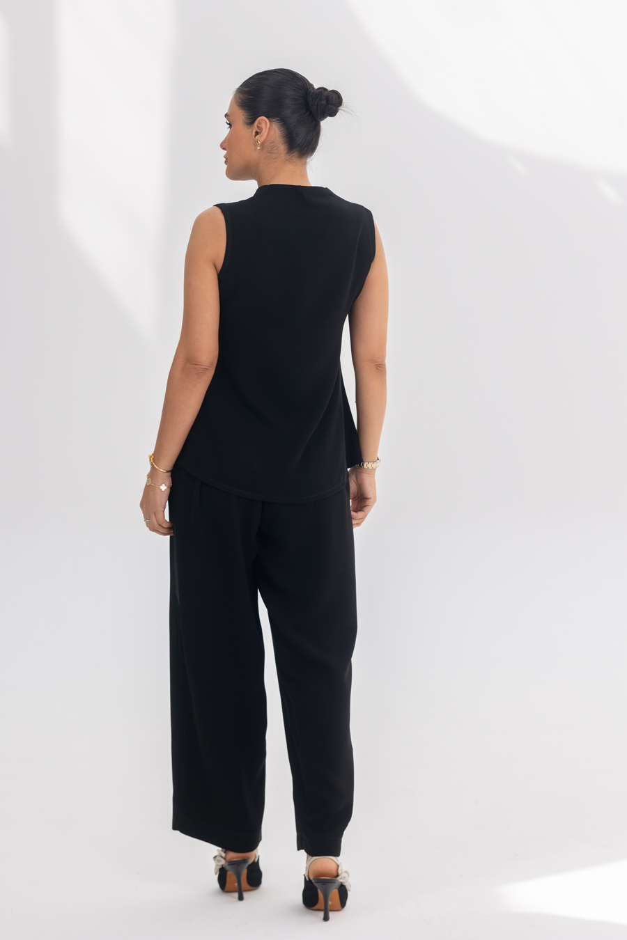 Woman wearing Noir Essential black crepe inner set with sleeveless top and wide-leg pants, styled for comfort and elegance.