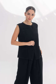Woman wearing black sleeveless crepe inner set with embroidery detail, styled elegant and comfortable.