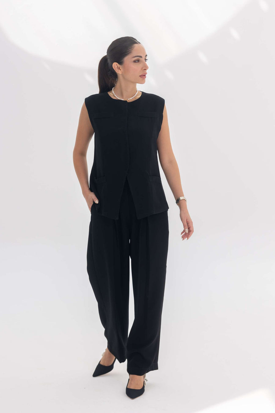 Woman wearing black sleeveless embroidered crepe inner set with wide-leg pants and black heels