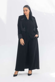 Woman wearing elegant black crepe blazer abaya with contrasting fabric details and long silhouette.