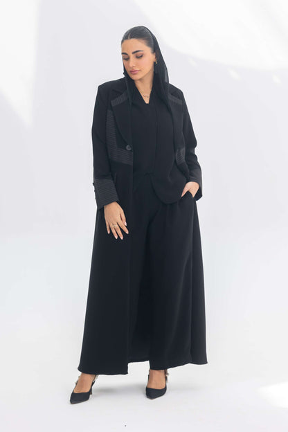 Woman wearing elegant black crepe blazer abaya with contrasting fabric details and long silhouette.