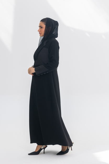 Elegant black crepe blazer abaya with contrasting fabric detail, worn with a black headscarf and heels, styled for modern sophistication.