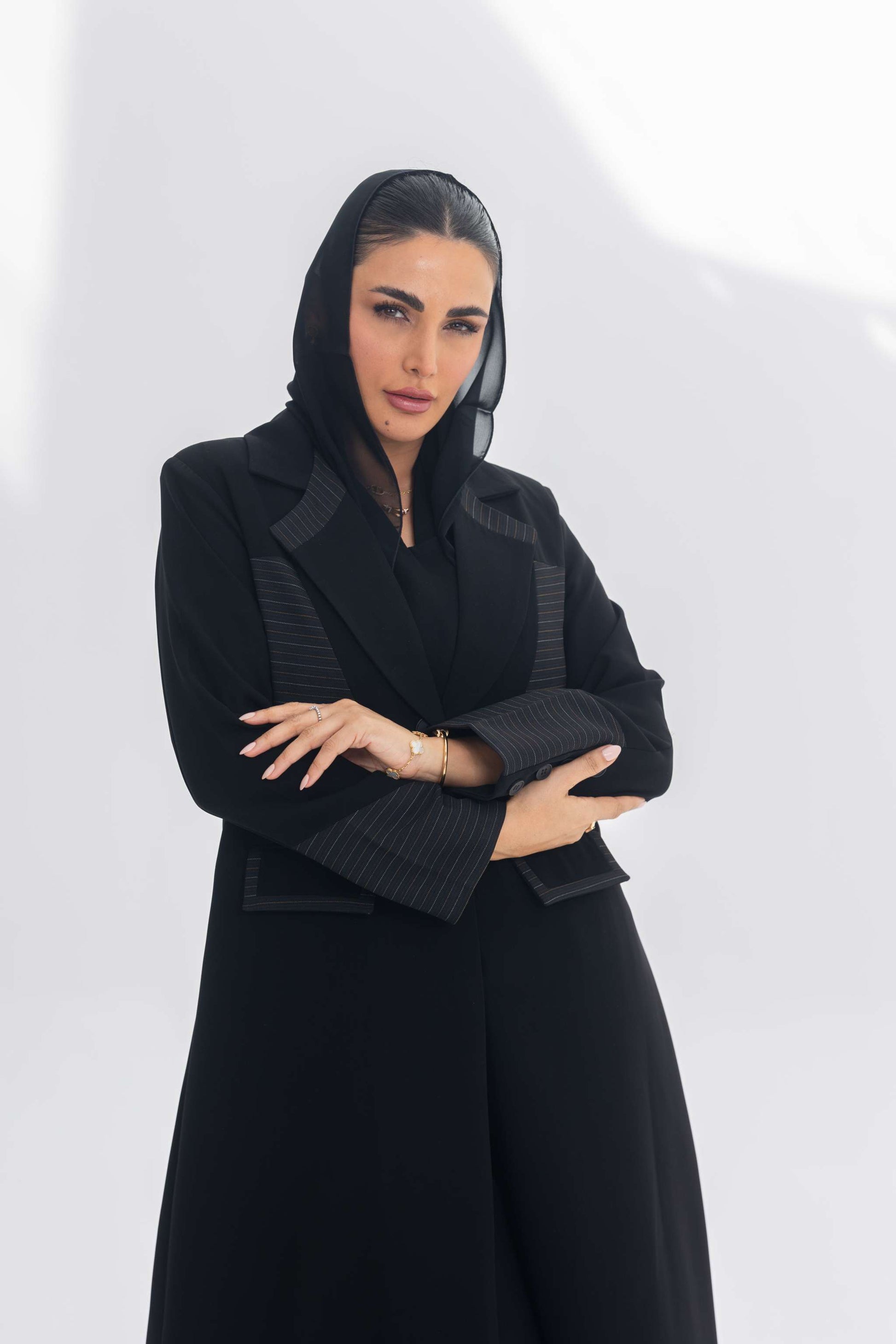 Black crepe blazer abaya with contrasting fabric details worn by confident woman with black headscarf