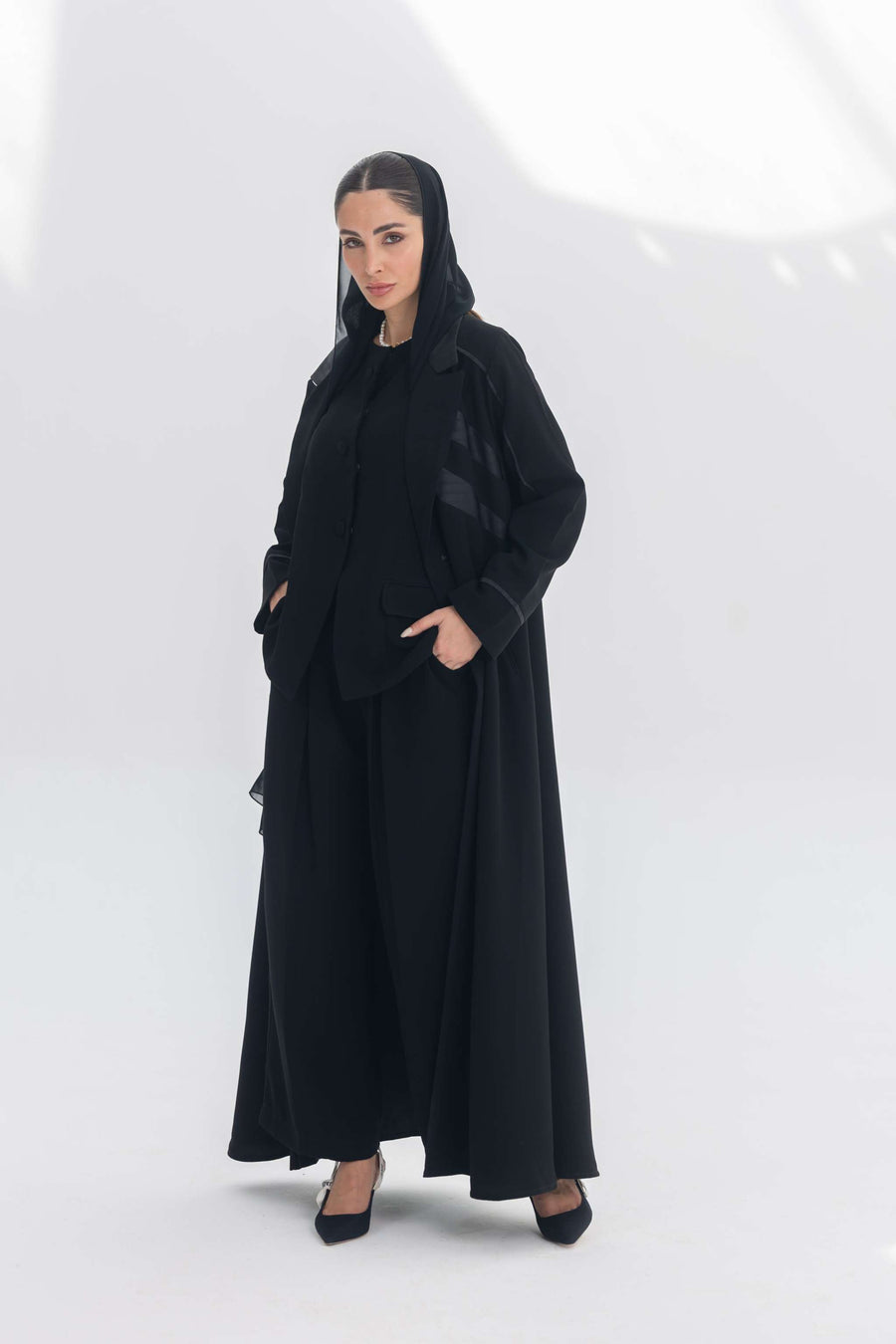 Woman wearing Noira Belle black crepe abaya with striped satin panels and hood.