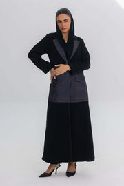 Woman wearing Blue Stitch abaya combining black crepe with denim fabric and modern design.