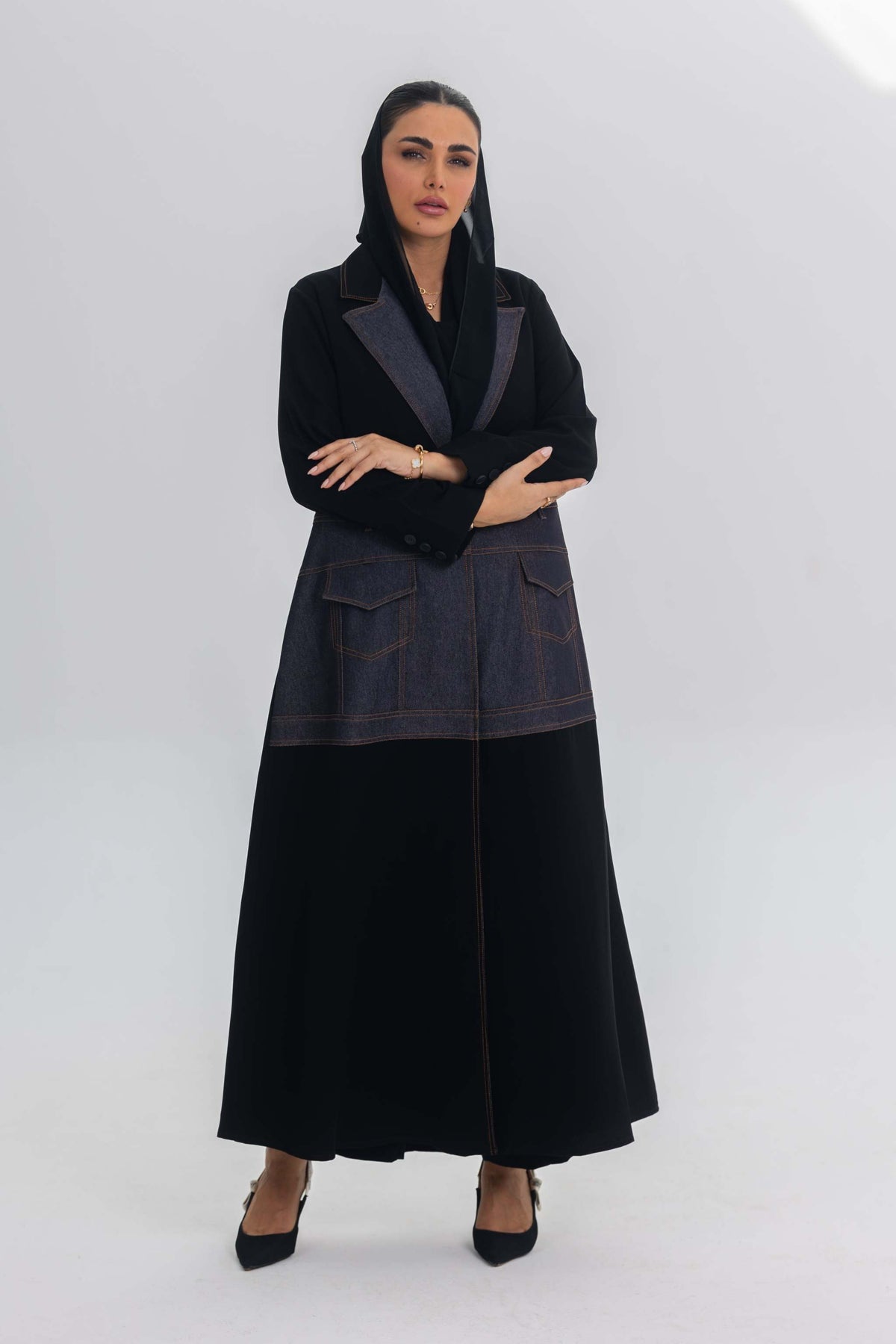 Woman wearing Blue Stitch abaya with black crepe and denim fabric fusion, modern and chic design