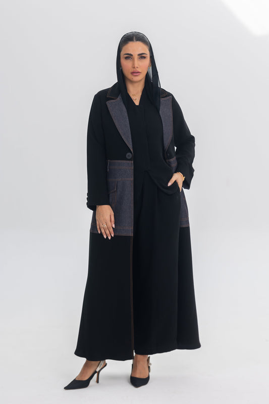Woman wearing elegant black crepe abaya with denim fabric accents and blue stitching, modern and chic design called Blue Stitch