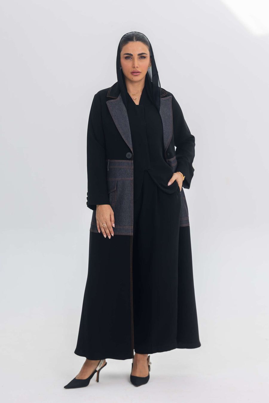 Woman wearing Blue Stitch abaya combining black crepe and denim fabric with a modern chic design