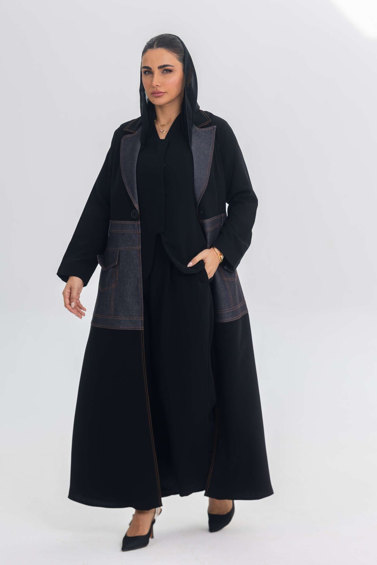 Woman wearing black crepe abaya with blue denim stitch detailing and pockets, modern stylish Blue Stitch design