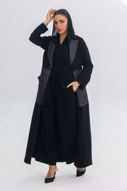 Woman wearing a black crepe abaya with denim fabric and blue stitch details, showcasing contemporary elegance.