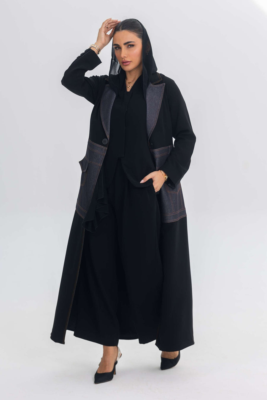 Woman wearing a black crepe abaya with denim fabric and blue stitch details, showcasing contemporary elegance.