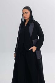 Woman wearing sleek black crepe abaya with edgy denim blue stitch detailing and modern design