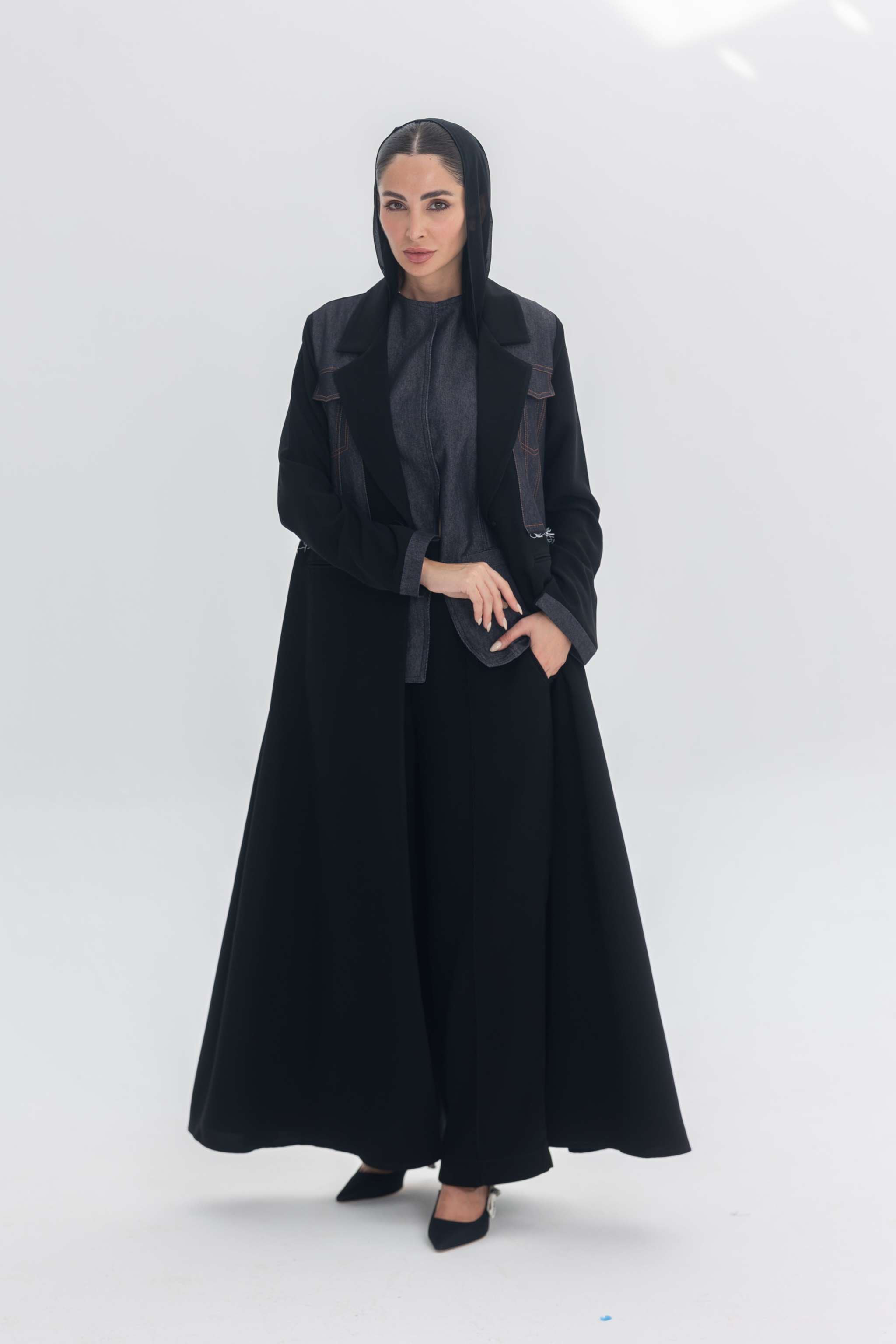 Woman wearing black crepe abaya with denim accents standing against white background Denim Veil