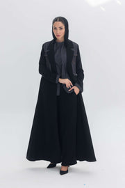 Woman wearing black crepe abaya with denim accents standing against white background Denim Veil