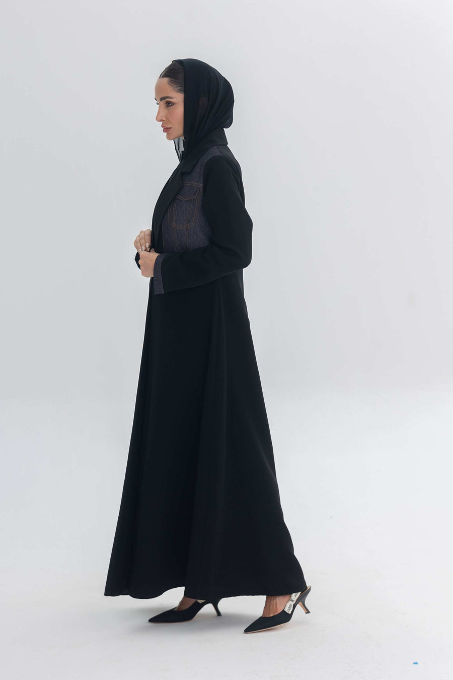 Woman wearing black crepe abaya with denim accents and matching veil in minimalist setting Denim Veil