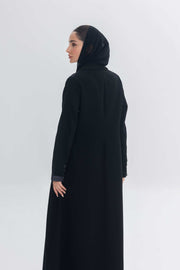 Woman wearing a black crepe abaya with denim accents and a matching black hijab, showcasing a modern and elegant modest fashion look called Denim Veil.
