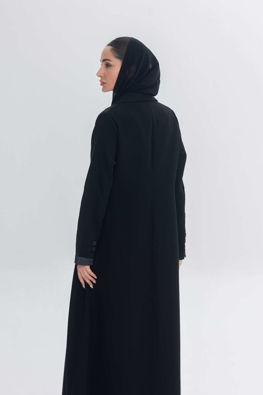 Woman wearing a black crepe abaya with denim accents and a matching black hijab, showcasing a modern and elegant modest fashion look called Denim Veil.