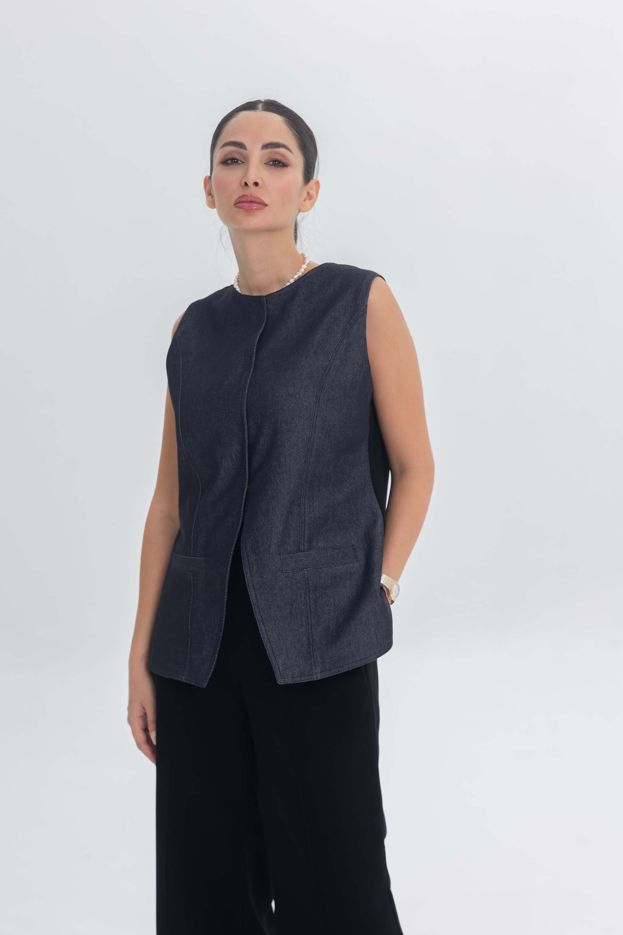Woman wearing True Bleu sleeveless denim-inspired top and black crepe pants against white background