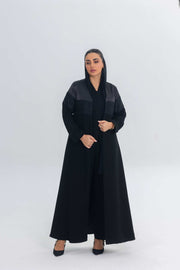 Elegant black satin abaya with crepe and delicate lace detailing, featuring a flowing silhouette and regal sheen.