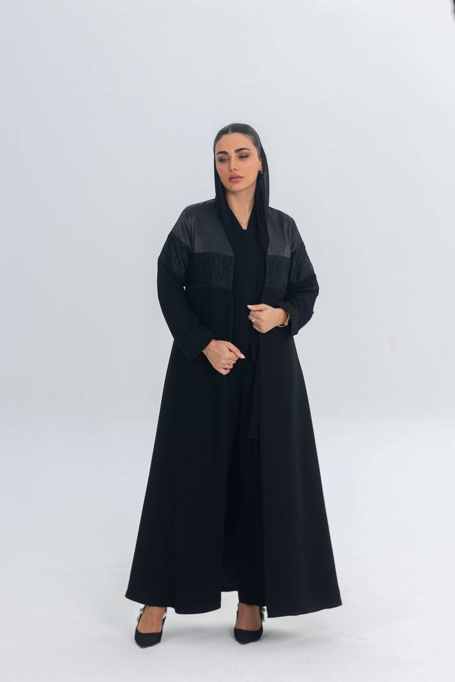 Elegant black satin abaya with crepe and delicate lace detailing, featuring a flowing silhouette and regal sheen.