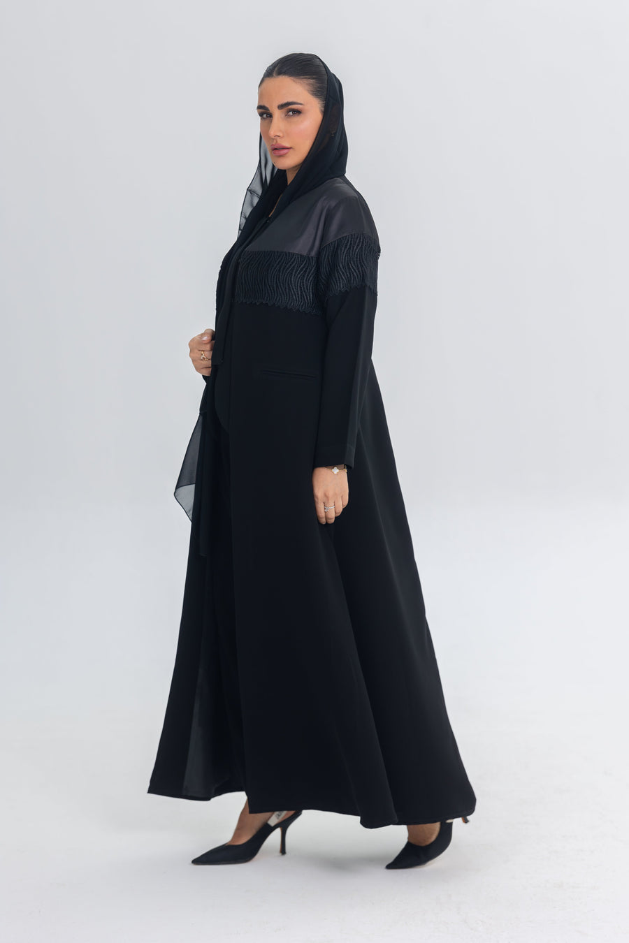 Elegant black satin and crepe abaya with intricate lace detailing and a flowing silhouette.
