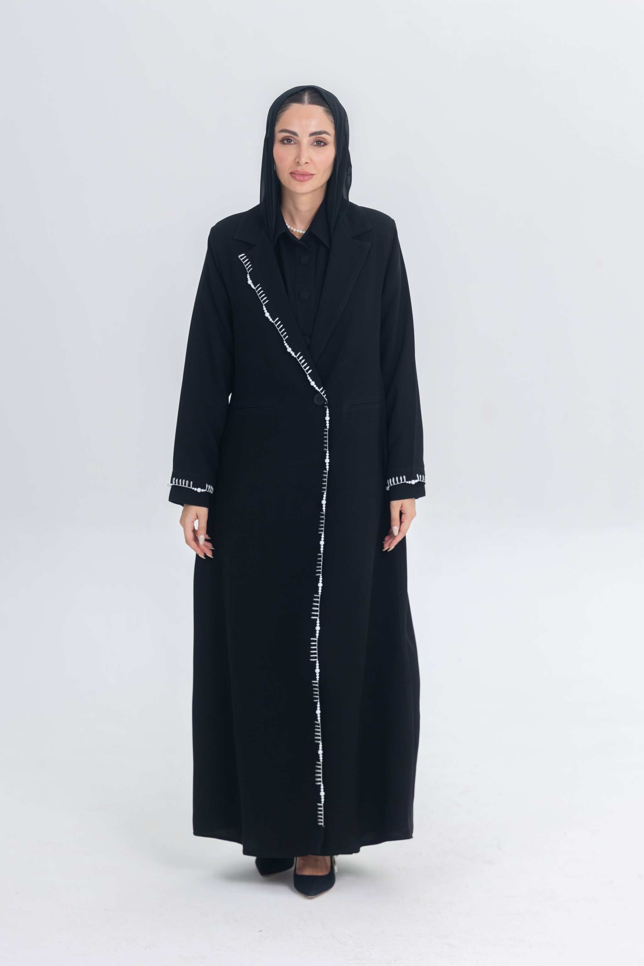 Woman wearing Pearl Noir black crepe blazer abaya with white pearl and bead embroidery detailing