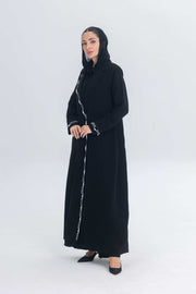 Black crepe blazer abaya with white pearl and bead embroidery, tailored silhouette, worn by woman in black heels and headscarf