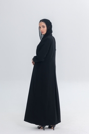 Woman wearing a black crepe blazer abaya with white pearl and bead embroidery, featuring a tailored silhouette and hand-stitched embellishments.