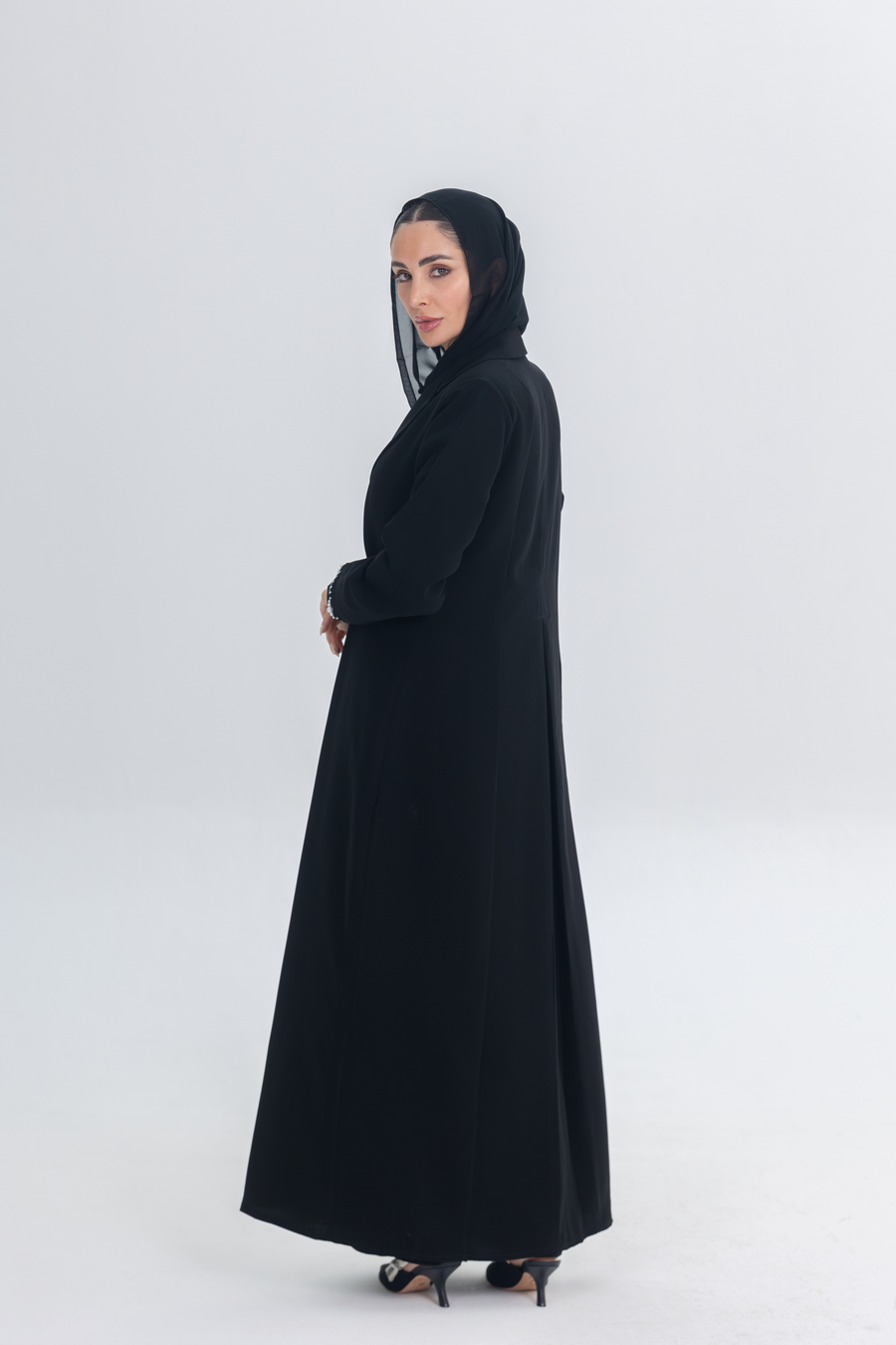 Woman wearing a black crepe blazer abaya with white pearl and bead embroidery, featuring a tailored silhouette and hand-stitched embellishments.