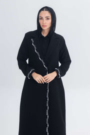 Woman wearing black crepe blazer abaya with white pearl and bead embroidery detailing