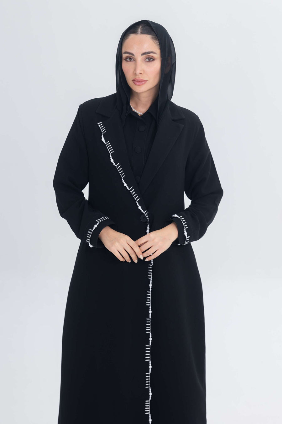 Woman wearing black crepe blazer abaya with white pearl and bead embroidery detailing