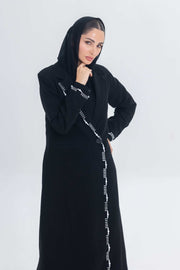 Woman wearing black crepe blazer abaya with white pearl and bead embroidery detailing.