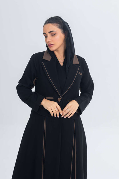 Black crepe blazer abaya with brown detailing and refined chestnut glow accents, styled on a woman with a sleek silhouette.