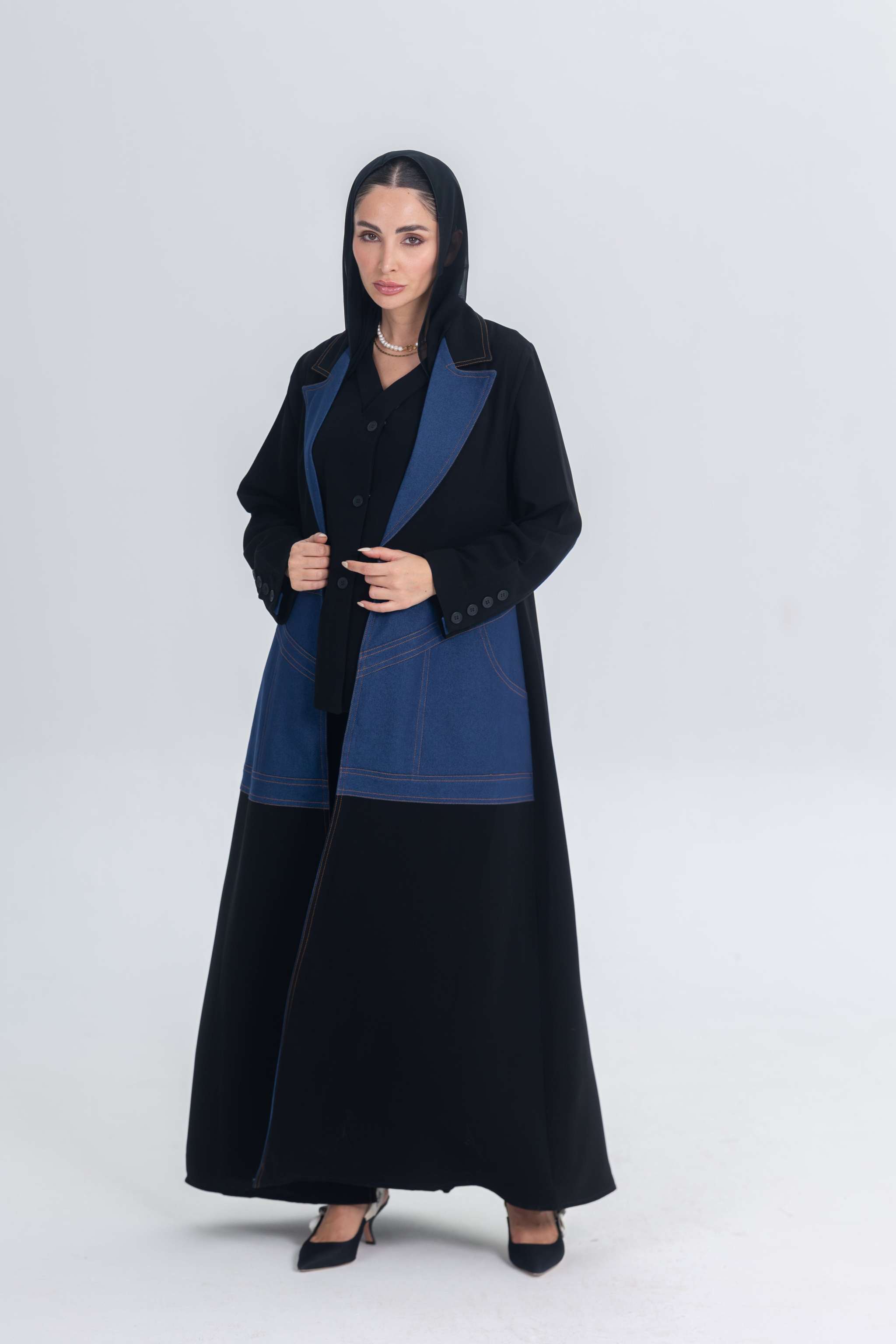 Woman wearing a black crepe abaya with structured denim accents and a tailored silhouette.