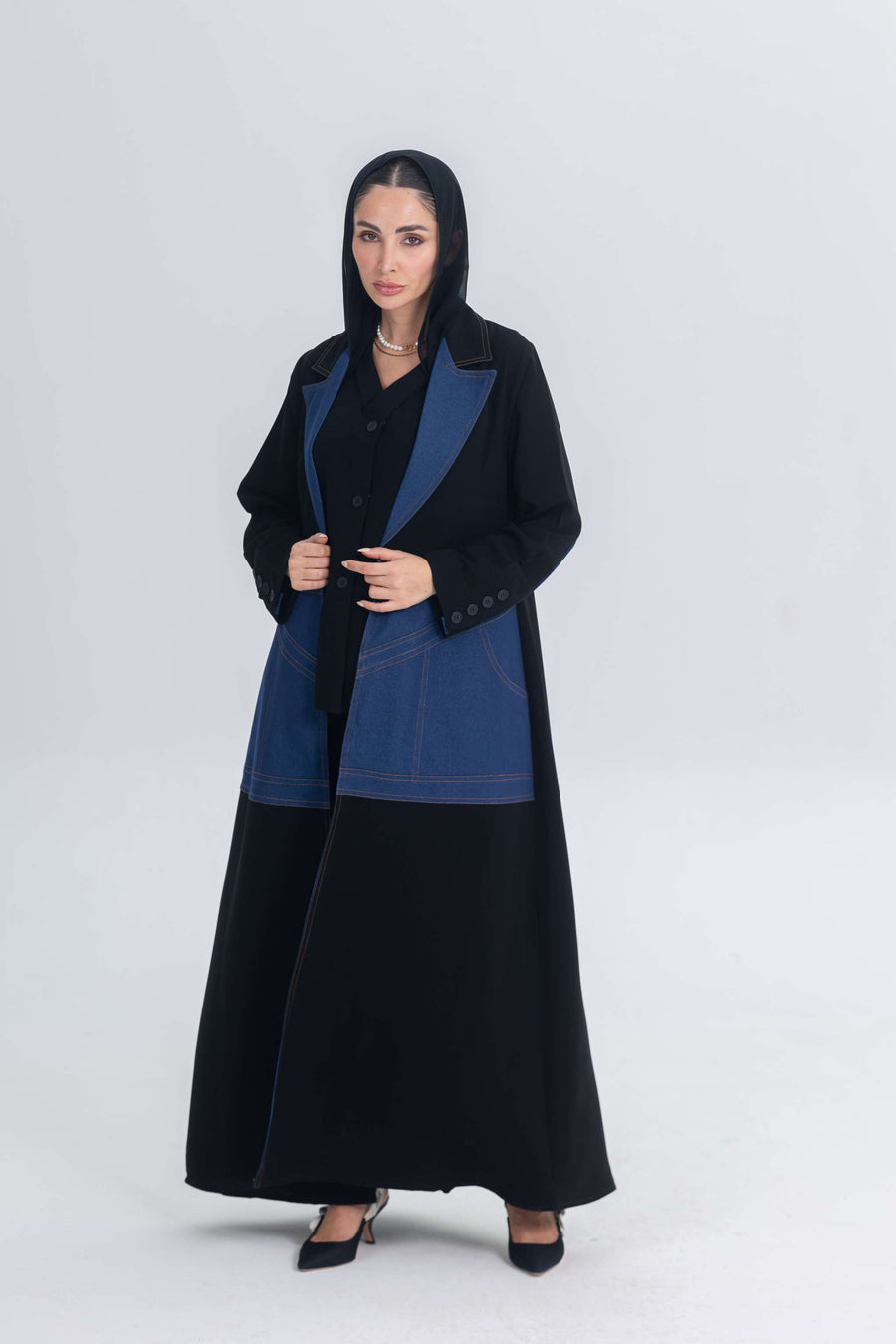 Woman wearing a black crepe abaya with structured denim accents and a tailored silhouette.