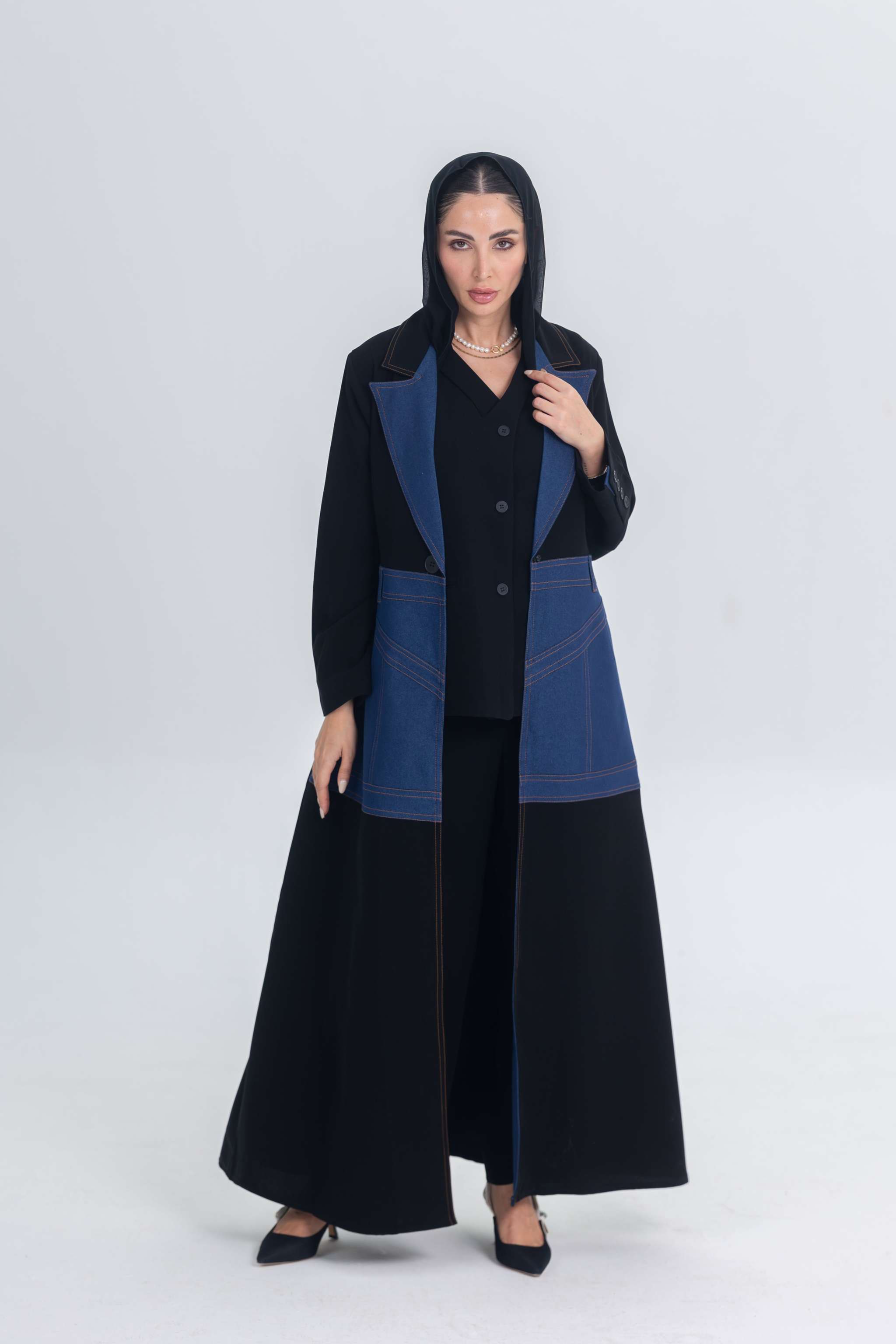 Black crepe abaya with denim panels and structured modern design worn by a woman