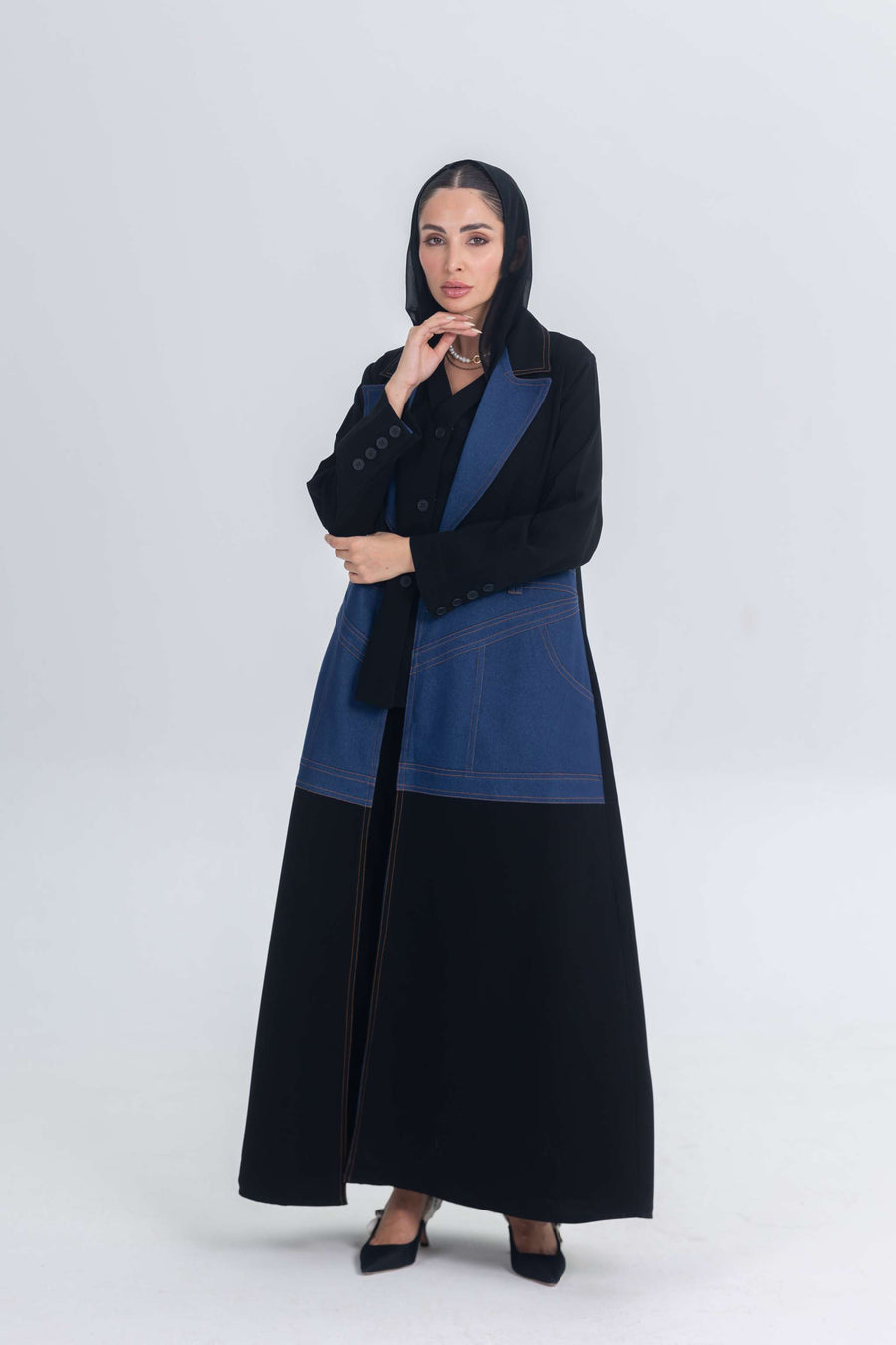 Woman wearing a black crepe abaya with denim panels, combining traditional and modern styles.