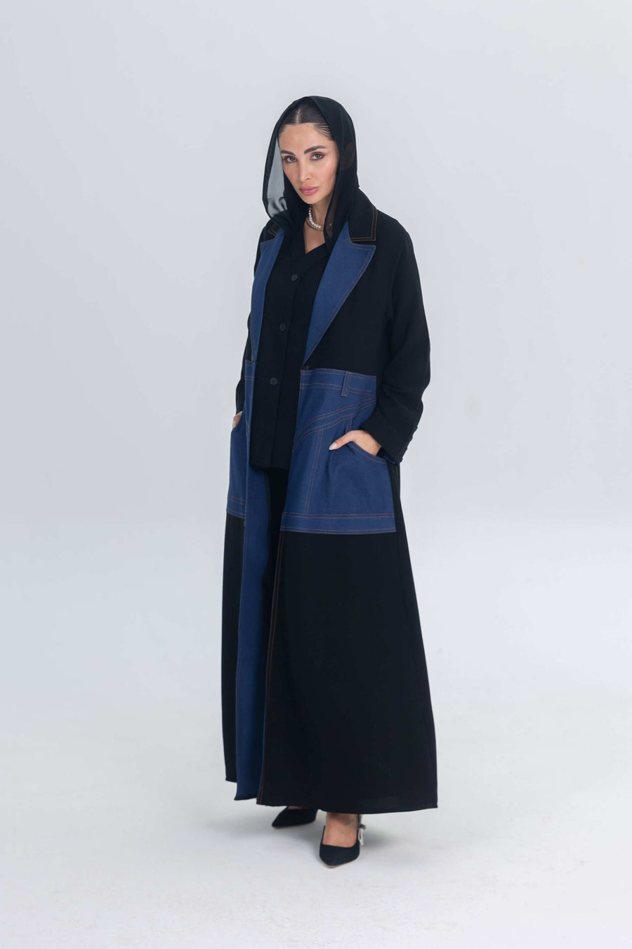 Woman wearing a black crepe abaya with denim panels and collar detailing in a formal style