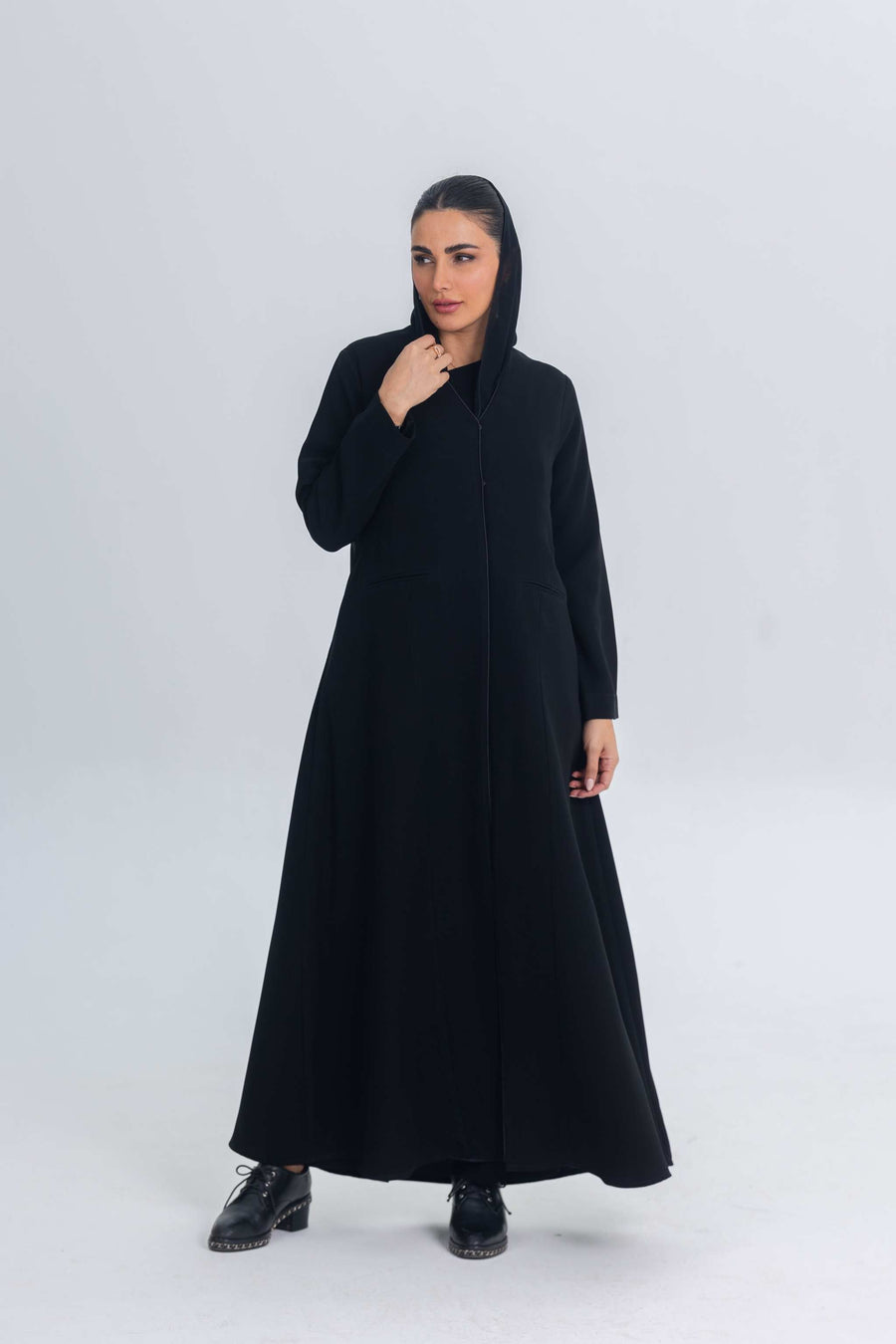 Black crepe abaya with subtle satin details, worn by a woman in a modest, elegant style.